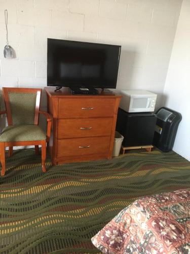 a bedroom with a dresser with a television and a bed at Moon Mist Motel in Meade