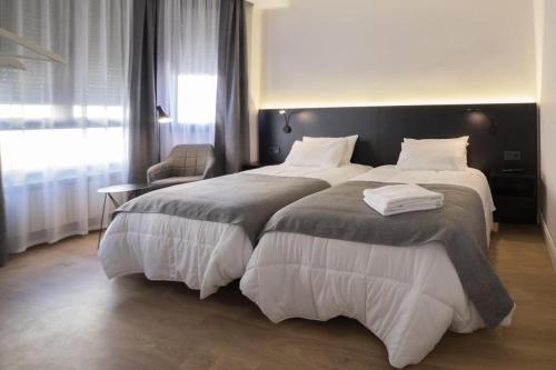 a hotel room with two beds and a chair at Apartamento céntrico Logroño Confort con Aire Acondicionado in Logroño