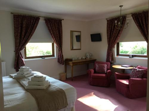 a bedroom with a bed and two chairs and windows at St Lawrence Guest House in Tenby
