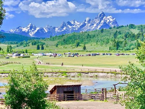 a field with a barn and mountains in the background at Heart Six Ranch in Moran