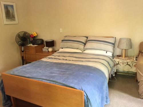 a bedroom with a bed and a dresser and lamp at Ivy's Cottage in Greytown
