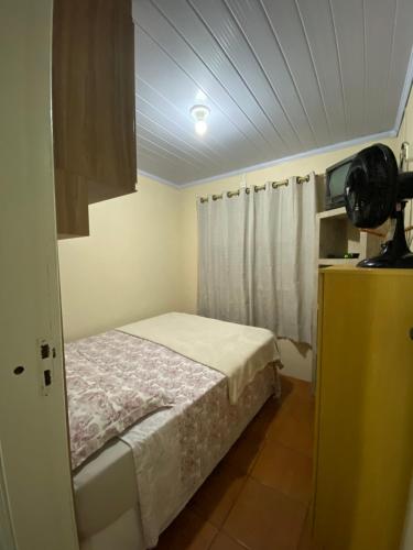 a small bedroom with a bed and a window at Edícula aconchegante 100m do Mar in Sombrio