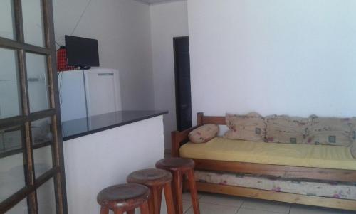 a bedroom with a bed with stools and a refrigerator at Chalés Pé na Areia - Ubatuba in Ubatuba