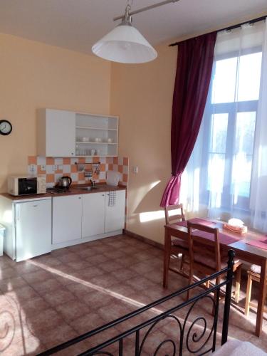 a kitchen with white cabinets and a table and a table and chairs at Penzion Pacovka in Chýnov