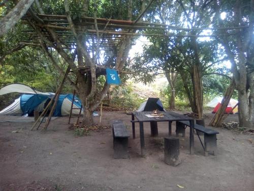 un campamento con tiendas de campaña, una mesa y un fuego en Hospedaje Eden, en Los Naranjos