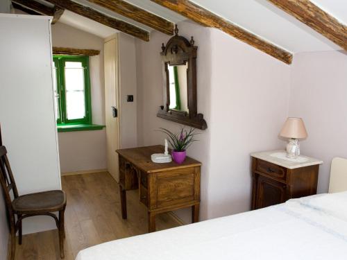 a bedroom with a bed and a desk and a mirror at Casetta Melon in Motovun