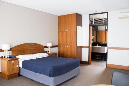 1 dormitorio con 1 cama con edredón azul y muebles de madera en Highlander Hotel Bar Kitchen Rooftop, en Adelaida