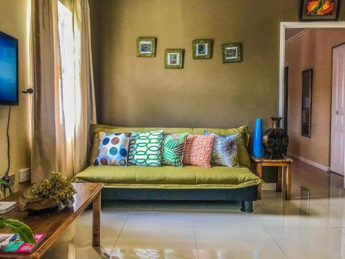 a living room with a green couch with colorful pillows at Dawn’s Comfort Zone in Kingston