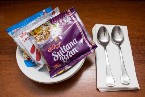 Highlander Hotel Bar Kitchen Rooftop في أديلايد: صحن مع كيس من السكر التوت باكت بجانب ملعقة