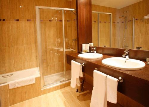 a bathroom with two sinks and a shower at Hotel Villa de Aranda in Aranda de Duero