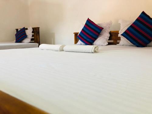 two beds with blue and white pillows on them at Kumari Guest House in Polonnaruwa