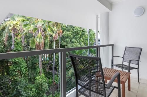 a balcony with a table and chairs and trees at Drift Palm Cove in Palm Cove