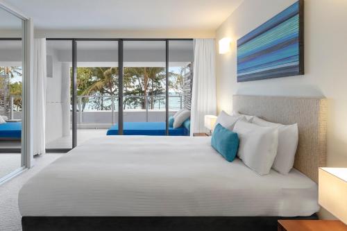 a bedroom with a large bed with a view of the ocean at Drift Palm Cove in Palm Cove