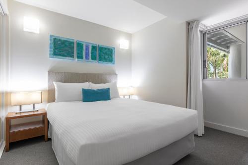 a bedroom with a large white bed and a window at Drift Palm Cove in Palm Cove