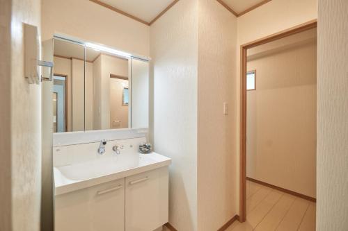 ein Bad mit einem Waschbecken und einem Spiegel in der Unterkunft FreedomHillsフリーダムヒルズA棟 in Tomigusuku
