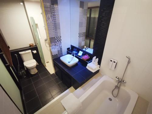 a bathroom with a tub and a toilet and a sink at Mandy Nok Hotel in Nakhon Si Thammarat