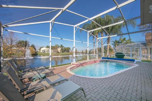 a swimming pool in a pavilion with chairs and a table at Mickey's Lake Villa 2 in Orlando