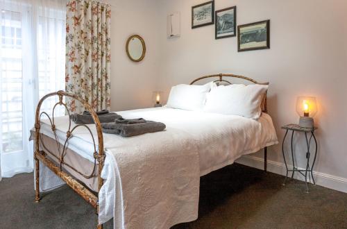 a bedroom with a bed with white sheets and a window at Kuranui Cottage in Thames