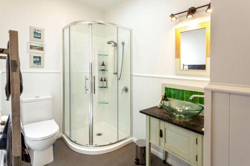 a bathroom with a shower and a toilet and a sink at Kuranui Cottage in Thames