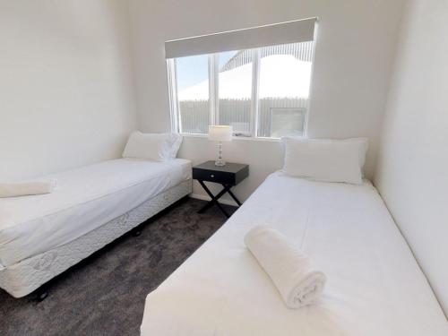 two beds in a white room with a window at Courtyard Loft 13 The Stables Perisher in Perisher Valley