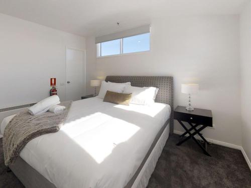 a bedroom with a large white bed and a desk at Courtyard Loft 13 The Stables Perisher in Perisher Valley