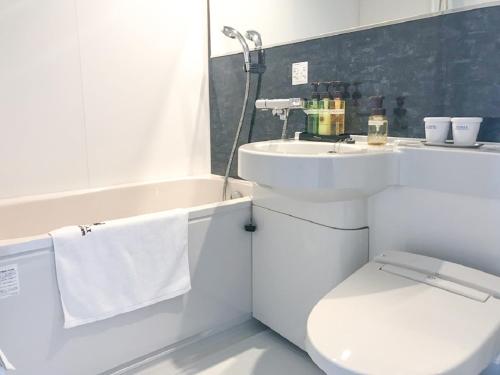 a white bathroom with a toilet and a sink at Hotel Livemax Fukushima Koriyama in Koriyama