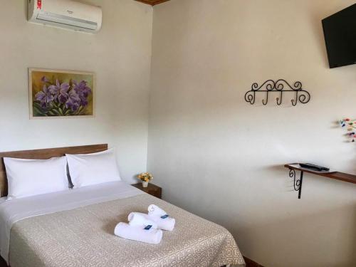 um quarto com uma cama com um bicho de peluche em Pousada Vovô Juca Tiradentes em Tiradentes