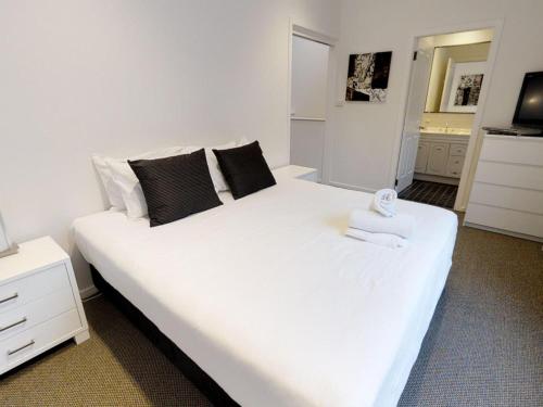 a bedroom with a large white bed with towels on it at Lodge Apartment 20 The Stables Perisher in Perisher Valley