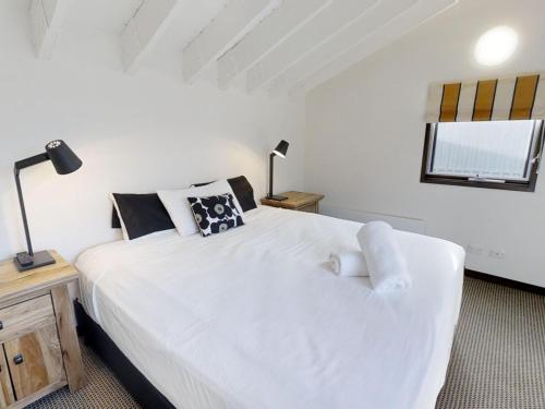 sypialnia z dużym białym łóżkiem i oknem w obiekcie Studio Loft 19 The Stables Perisher w mieście Dolina Perisher