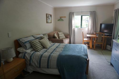 a bedroom with a bed and a living room at Ivy's Cottage in Greytown