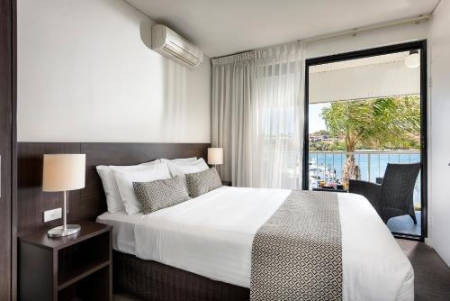 a bedroom with a large bed and a large window at Pier 21 Apartment Hotel Fremantle in Fremantle