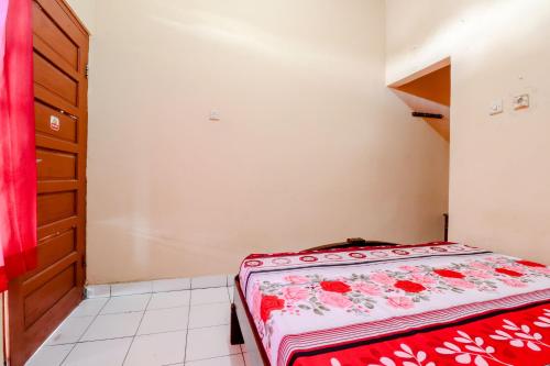 a small bedroom with a bed with a red blanket at Griya Barokah in Kalasan