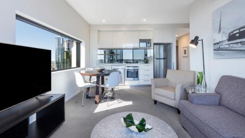 a living room filled with furniture and a tv at Oaks Melbourne on William Suites in Melbourne