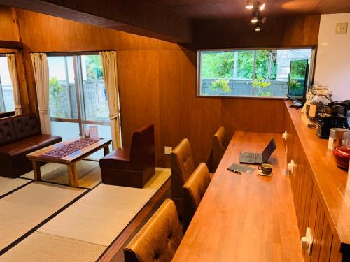 ein Esszimmer mit einem langen Holztisch und Stühlen in der Unterkunft 宿＆喫茶 アガリメージョー in Uruma