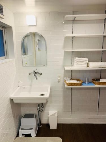 ein weißes Badezimmer mit Waschbecken und Spiegel in der Unterkunft 宿＆喫茶 アガリメージョー in Uruma