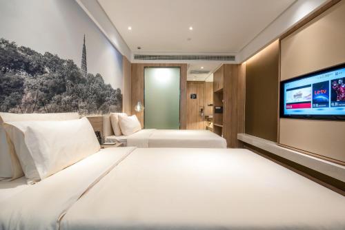 a hotel room with two beds and a flat screen tv at Atour Hotel Hangzhou West Lake in Hangzhou