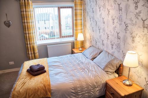 a bedroom with a bed and two lamps and a window at North Coast Property - North Coast House in Thurso