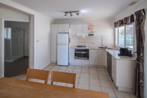 a kitchen with white appliances and a table and chairs at Ingenia Holidays Lake Macquarie in Mannering Park