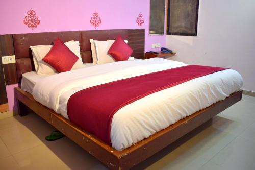 a bedroom with a large bed with red and white pillows at Radhe-The Hotel in Vadodara