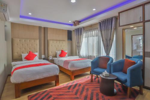 um quarto de hotel com duas camas e duas cadeiras em Hotel Marinha em Pashupatināth