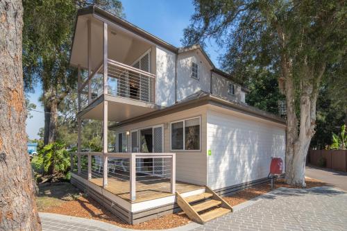 a house with a balcony and a tree at Ingenia Holidays Lake Macquarie in Mannering Park