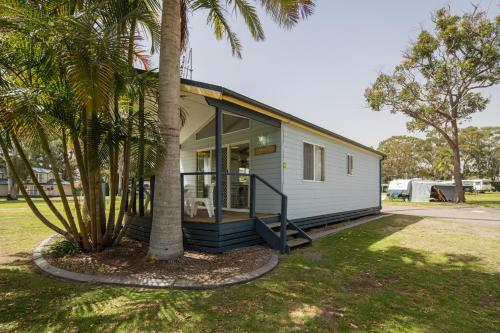 a small white house with a palm tree at Ingenia Holidays Lake Macquarie in Mannering Park