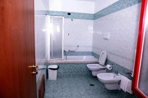 uma casa de banho com 2 WC, uma banheira e um lavatório. em Hotel Castelmonardo em Filadelfia