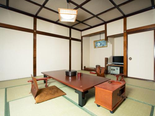 a room with a table and chairs and a tv at Sakadojo in Minami Uonuma
