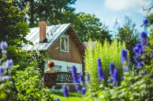 a woman sitting on a bench in front of a house at Disponentparken Café och Bed & Breakfast in Grängesberg