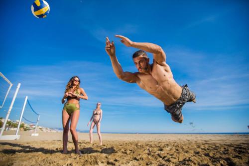 a man jumping to hit a volley ball on the beach at Club Big Blue Suit Hotel - All Inclusive Plus in Alanya