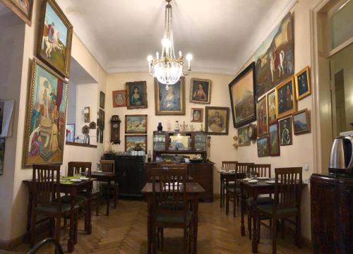 un restaurante con mesas, sillas y cuadros en las paredes en Gutsa Artists Mini-Hotel, en Tiflis
