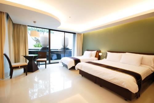 a hotel room with two beds and a window at Tara Mantra Cha-Am Resort in Cha Am