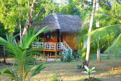 a small wooden house with a thatch roof at Rock Pool Residence in Tangalle