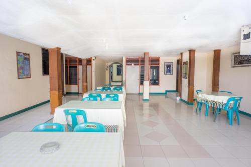 a room with several tables and blue chairs at OYO 2180 Vina Vira Hotel in Lhokseumawe